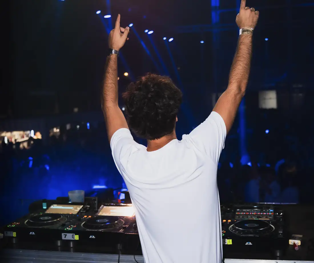 DJ con los brazos en alto frente a la pista en un evento de Bongala Studio
